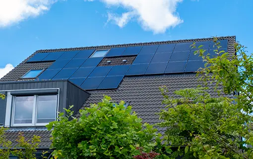 Nowoczesne panele solarne Solemark zamontowane na ciemnej dachówce wielorodzinnego budynku mieszkalnego